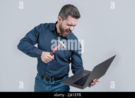 Wütend Mann brechen Laptop schlagen Notebook mit Hammer grauen Hintergrund, Computer Wut Stockfoto