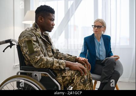 Paraplegischer Soldat im Rollstuhl im Gespräch mit Therapeut Stockfoto