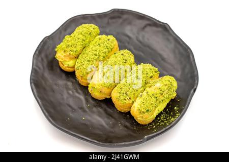 Eclair Kuchen mit Pistazien isoliert auf weißem Hintergrund. Nahaufnahme. Stockfoto