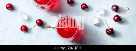 Cocktail garniert mit Kirschpanorama, frischem Preiselbeersaft mit Eis auf dunklem Grund, zwei Gläsern, einem flachen Lay, von oben geschossen Stockfoto