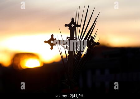 Karwoche. Prozessionskreuz und Zweige in wunderschöner Sonnenuntergangsszenerie. Traditionelle katholische Feier Palmsonntag. Christlicher Glaube. Religiöse Symbole Stockfoto