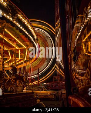 Leichte Spuren vom Karussell und Riesenrad im Hintergrund im St Giles fair, Oxford.  Beide Spuren sind Refelected in der bequem geparkten artic Stockfoto