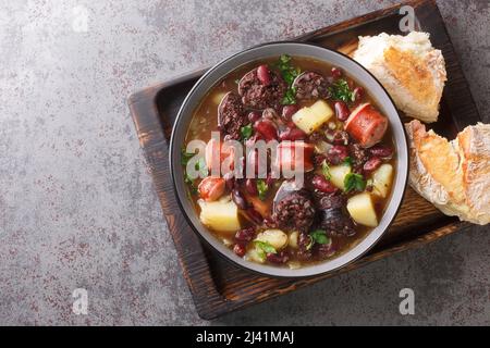 SOPA de pedra Portugiesische Steinsuppe Kombination von Bohnen und Würstchen wie Chourico und Morcilla in der Nähe auf dem Teller auf dem Tisch. Horizontal oben Stockfoto