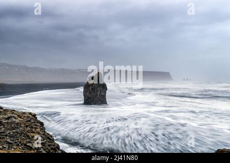 Arnardrangur, oder Eagle Rock, in Dyrholaey, Südisland. Das Gestein wird so genannt, weil Adler es früher nisten. Zusammensetzung der Langzeitbelichtung mit R Stockfoto