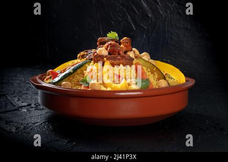 Couscous mit Fleisch und Gemüse, traditionelles marokkanisches Gericht, mit Kichererbsen und Koriander, auf schwarzem Hintergrund Stockfoto