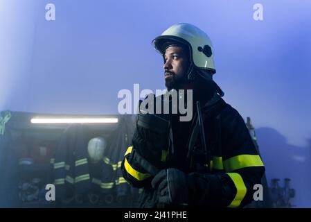 Junger afroamerikanischer Feuerwehrmann in der Feuerwache bei Nacht. Stockfoto