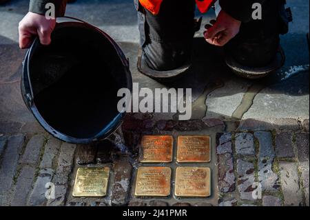 Ein Mann wird gesehen, wie er die Stolpersteine reinigt, nachdem er gerade platziert wurde. Als Beginn einer neuen Tradition, an die jüdischen Opfer des Nazi-Regimes zu erinnern, wurden die ersten sechzehn Stolpersteine während einer feierlichen Zeremonie und der Anwesenheit von Angehörigen der Opfer auf dem Bürgersteig vor dem Haus, in dem die Opfer lebten oder arbeiteten, aufgestellt. Stolpersteine sind oben mit einer Messingplatte bedeckte Stolpersteine, die an verfolgte und ermordete Juden erinnern, die Opfer des Nazi-Regimes wurden. Etwa 450 jüdische Bürger von Nijmegen überlebten den Krieg während des Zweiten Weltkriegs nicht. (Foto von Einem Stockfoto