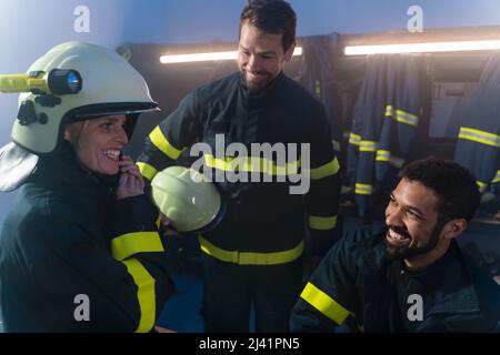 Glückliche Feuerwehrmänner Männer und Frauen, die sich nach dem Einsatz in der Feuerwehr unterhalten Stockfoto