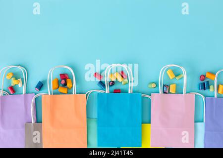 Flaches Lay, Papiertüten und Kaugummis auf blauem Hintergrund. Stockfoto