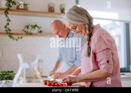 Glückliches Seniorenpaar, das zu Hause zusammen kocht. Stockfoto