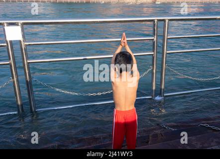 Junges Kind, das am Morgen eine religiöse Pryer des Flusses aus flachem Winkel Bild macht, wird bei haridwar uttrakhand india aufgenommen. Stockfoto