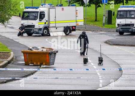 Belfast, Nordirland. 11.. September 2013 - eine ATO-Armee nähert sich einem Objekt, das in einer Wohnstraße im Stadtteil Twinbrook in West Belfast gefunden wurde, wobei ein bewaffneter Soldat hinter ihm Schutz bietet. PSNI haben bestätigt, dass es sich um ein brauchbares Gerät handelt, das zur Untersuchung weggenommen wurde. Stockfoto