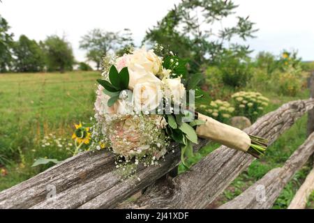 Blumenstrauß aus weißen und rosa Rosen mit Babys Atem auf Split Rail Zaun in Farm Field Stockfoto