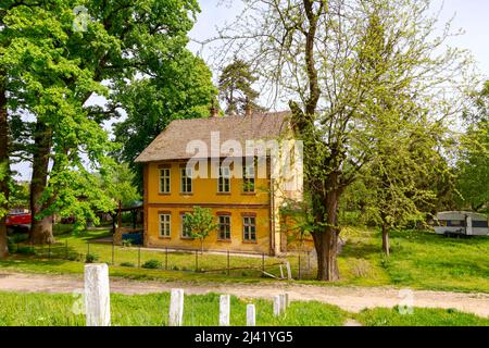 Ivanovo, Vojvodina, Serbien - 17. April 2016: Altes Wohnhaus mit gelber Fassade mit Zierfenstern, Außenansicht eines alten Gebäudes. Stockfoto