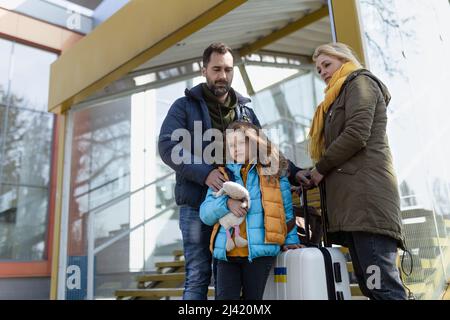 Ukrainische Flüchtlingsfamilie mit Gepäck am Bahnhof zusammen, ukrainisches Kriegskonzept. Stockfoto