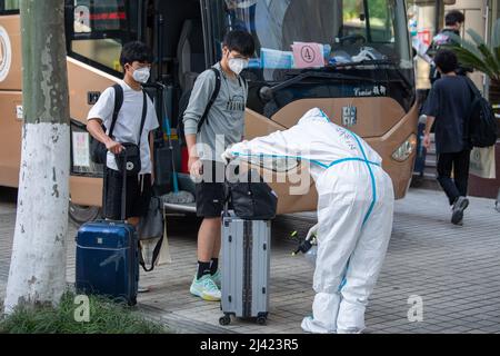 (220411) -- HANGZHOU, 11. April 2022 (Xinhua) -- Ein Mitarbeiter desinfiziert das Gepäck von Personen, die vor einem Hotel in Hangzhou, der ostchinesischen Provinz Zhejiang, in Quarantäne gestellt werden, am 11. April 2022. Die Stadt Hangzhou hat Quarantänezimmer angeboten, um Shanghai während des Wiederauflebens der COVID-19 zu helfen. Die Räume werden genutzt, um Personen zu isolieren, die enge Kontakte und sekundäre enge Kontakte von COVID-19-Fällen in Shanghai sind. Die humanistische Versorgung an isolierten Standorten wurde verstärkt, wobei der Schwerpunkt auf der Sicherheit des Lebens, medizinischen Dienstleistungen, psychiatrischer Beratung und personalisierten Dienstleistungen liegt. (Xinhua/Jiang Han) Stockfoto