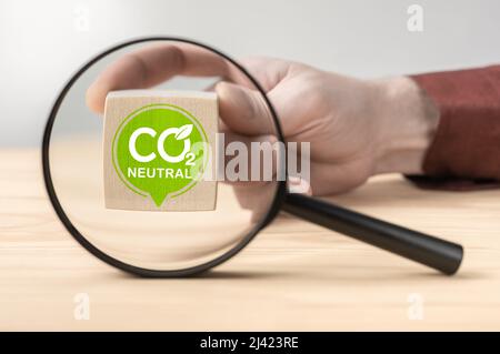 CO2 Neutralzeichen durch Vergrößerungsglas auf Holztisch. CO2 Neutrales Engagement in Wirtschaft, Finanzen und Industrie zur Reduzierung der Kohlendioxidemissionen Stockfoto