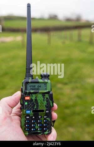 Der Mann hält ein zwei-Wege-Radio mit Tarnmuster. Stockfoto