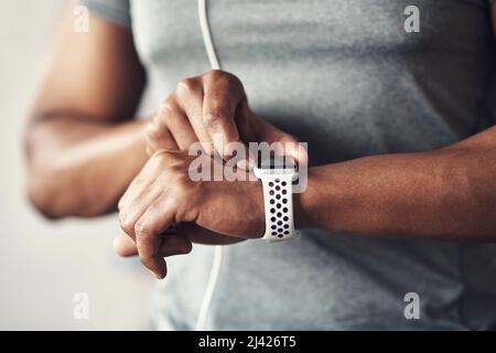 Die Zahlen belegen, dass Sie Fortschritte machen. Nahaufnahme eines nicht erkennbaren Mannes, der seine Armbanduhr beim Training zu Hause überprüft. Stockfoto