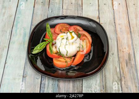 Burrata passt gut zu den meisten Produkten, und Sie können es kombinieren, indem Sie die äußeren Teile von Mozzarella abschneiden und sie zu Salaten oder Pasta-Gerichten hinzufügen. Stockfoto