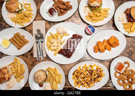 Amerikanische Fast-Food-Gerichte mit verschiedenen Burgern, Pommes Frites, frittierten Zwiebelringen, Büffelflügeln, Hähnchenflügeln, Mozzarella-Finger, grillrippen und Fré Stockfoto