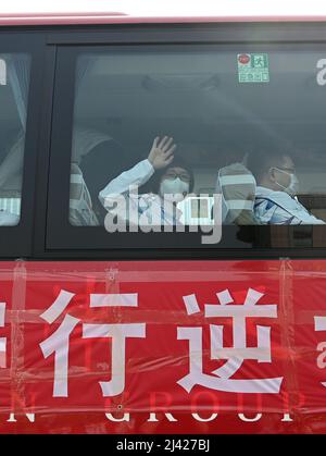 (220411) -- TIANJIN, 11. April 2022 (Xinhua) -- Xu Ning winkt ihrer Familie durch das Fenster eines Busses, als sie nach Shanghai, im nordchinesischen Tianjin, fährt, 11. April 2022. Tianjin entsandte am Montag ein Team von 78 medizinischen Mitarbeitern der Traditionellen Chinesischen Medizin (TCM), um Shanghai bei der Bekämpfung der COVID-19-Pandemie zu unterstützen. Xu Ning, stellvertretender Chefarzt des ersten Lehrkrankenhauses der Universität für traditionelle Chinesische Medizin in Tianjin, ist einer von ihnen. In den letzten zwei Jahren war sie viele Male auf den Stationen des Tianjin Haihe Krankenhauses, um gegen die Pandemie zu kämpfen, und sammelte viele Erfahrungen Stockfoto