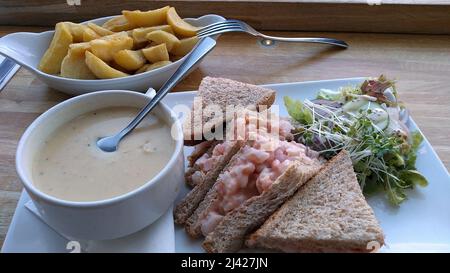 LYTHAM. LANCASHIRE. ENGLAND. 11-14-21. Eine Mahlzeit aus Pilzsuppe, Garnelen auf Vollkornbrot und eine Beilage von Chips. Sie werden durch natürliches Licht fro beleuchtet Stockfoto