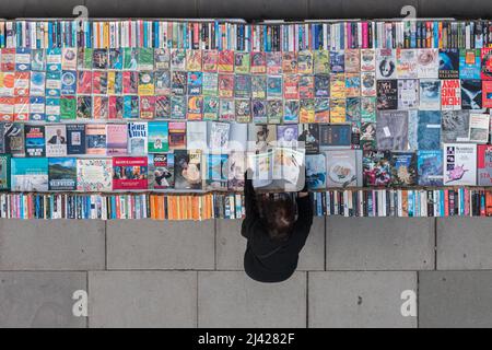 London, Vereinigtes Königreich - 22. Oktober 2016: Alleinerziehende Frau blättert durch Seiten eines Gebrauchtbuches im Buchmarktstand auf der Southbank in London Stockfoto