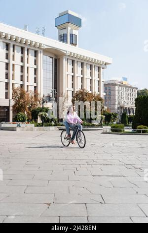 Positives junges Paar, das Fahrrad auf der städtischen Straße in der Stadt reitet Stockfoto