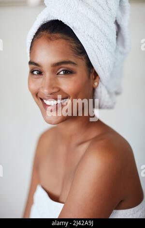 Schönes Herz, schönes Gesicht. Porträt einer attraktiven und entspannten jungen Frau, die zu Hause in ein Handtuch gehüllt ist. Stockfoto