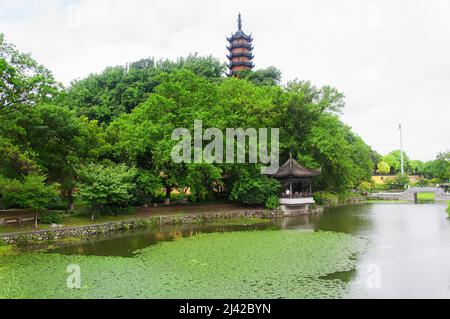 Zhenjiang, China. 12. August 2017. Cishou-Pagode auf einem Hügel über einem mit Seerosen gefüllten Teich im malerischen Gebiet des Jinshan-Tempels an einem bewölkten Tag in Zhenjiang Stockfoto