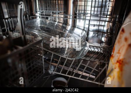 Nahaufnahme schmutzige Glasauflaufform auf der unteren Ablage in der Spülmaschine mit schmutzigem Geschirr gefüllt schmutziges transparentes Glas hitzebeständiges Gefäß in der Spülmaschine Stockfoto