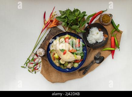 Grünes Kerrys mit Hühnchen und grün-weißen Sorten thailändischer Auberginen (Kaeng Khiao wan) in einer Keramikschale serviert mit thailändischen Reisnudeln (fermentierter Reis f Stockfoto