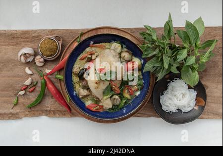 Grünes Kerrys mit Hühnchen und grün-weißen Sorten thailändischer Auberginen (Kaeng Khiao wan) in einer Keramikschale serviert mit thailändischen Reisnudeln (fermentierter Reis f Stockfoto