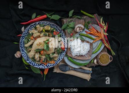 Grünes Kerrys mit Hühnchen und grün-weißen Sorten thailändischer Auberginen (Kaeng Khiao wan) in einer Keramikschale serviert mit thailändischen Reisnudeln (fermentierter Reis f Stockfoto