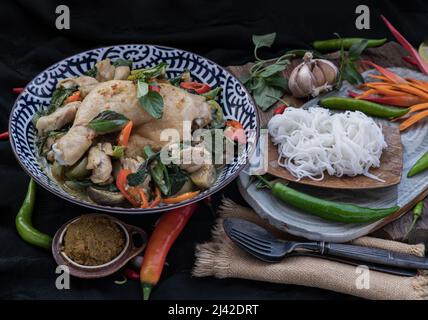 Grünes Kerrys mit Hühnchen und grün-weißen Sorten thailändischer Auberginen (Kaeng Khiao wan) in einer Keramikschale serviert mit thailändischen Reisnudeln (fermentierter Reis f Stockfoto