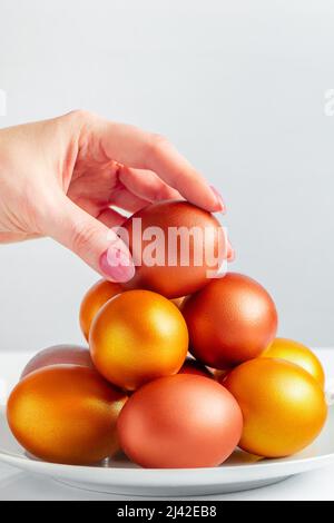 Frau legt goldenes Osterei in Stapel. Happy Holiday Konzept. Stockfoto