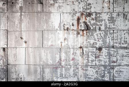 Grungige Betonwand mit beschädigten Schichten von Stuck und Farbe, städtische Hintergrundstruktur Stockfoto