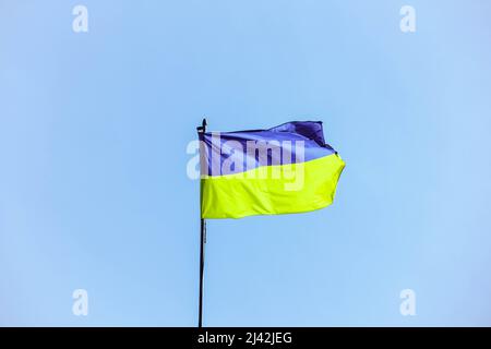 Ukrainische Flagge in den Strahlen der aufgehenden Sonne auf einem Hintergrund des Himmels. Blaue und gelbe Nationalflagge der Ukraine auf einem Fahnenmast. Offizielles Symbol und Zeichen Stockfoto