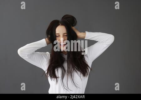 Lächelnde Frau mit geschlossenen Augen auf grauem Hintergrund Stockfoto