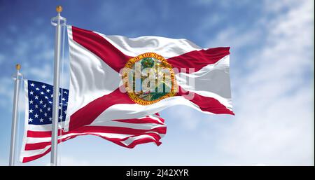 Die Florida-Staatsflagge winkt zusammen mit der Nationalflagge der Vereinigten Staaten von Amerika. Im Hintergrund ist der Himmel klar. Stockfoto