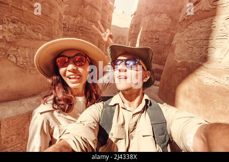 Ein verliebtes Paar macht während der Flitterwochen-Tour ein Selfie-Foto zwischen den riesigen Säulen im Karnak-Tempel in Luxor Stockfoto