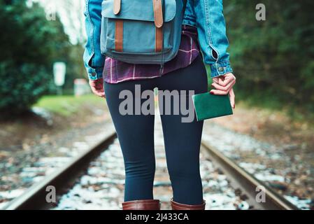 Das Buch, das mich an die Plätze bringen wird. Rückansicht einer unkenntlichen Frau, die auf Bahngleisen im Freien läuft. Stockfoto