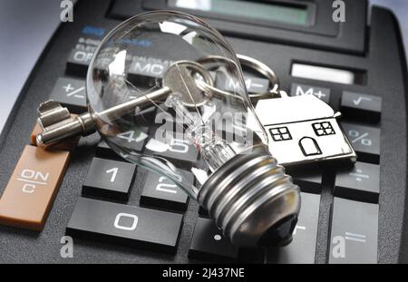 HAUSSCHLÜSSEL UND SCHLÜSSELRING MIT GLÜHBIRNE AUF RECHNER RE DIE LEBENSHALTUNGSKOSTEN STROM STEIGENDE PREISE HAUSHALTSRECHNUNGEN ELEKTRO GROSSBRITANNIEN Stockfoto