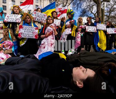 Abend, 9.. April. Die Demonstranten trugen traditionelle ukrainische Kleidung, die mit roter Farbe befleckt war, um den Schrecken der russischen Armee zu wiederholen. Stockfoto
