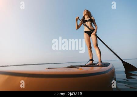 Schöne junge Frau genießen die Natur auf einem SAP-Board reisen. Stockfoto