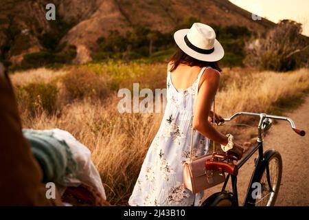 Wohin du gehst, gehe ich. Aufnahme einer unkenntlichen Frau, die mit dem Fahrrad in der Natur unterwegs ist. Stockfoto