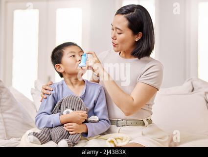 Atmen Sie langsam ein. Aufnahme einer Frau, die ihrem Sohn mit seinem Asthmainhalator half. Stockfoto