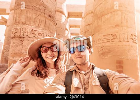 Ein verliebtes Paar macht während der Flitterwochen-Tour ein Selfie-Foto zwischen den riesigen Säulen im Karnak-Tempel in Luxor Stockfoto