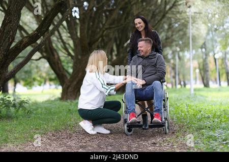 Zwei Frauen und ein Mann im Rollstuhl sprechen im Park Stockfoto